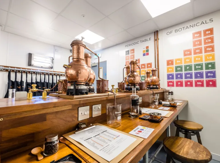 Distillery bottles and vats on a desk in a botanical room.