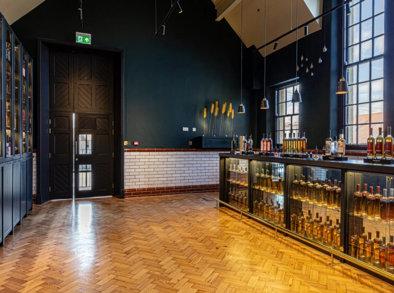 A room with bottles of whisky in glass cabinets and black cabinets.