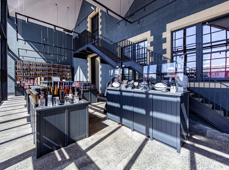 A distillery shop and refreshment area bathed in sunlight from the glass windows.