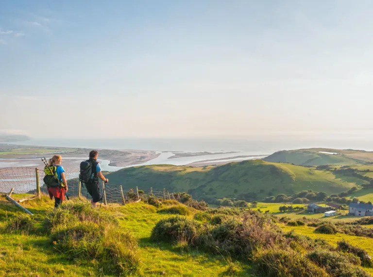 Couple walking on Wales Coast Path overlooking Dovey estuary near Aberdovey.