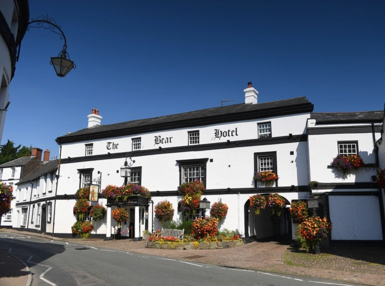 A traditional hotel adorned with flower baskets and window boxes in a town.