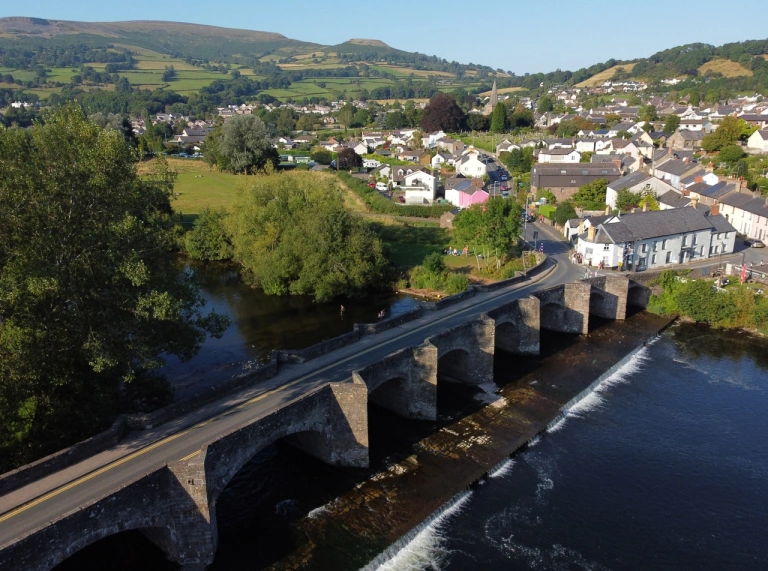 An aerial view of a road bridge running over a river leading to a town.