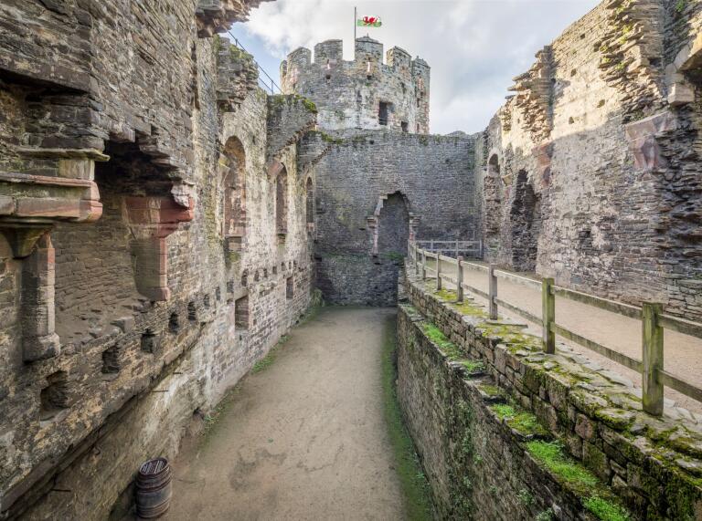 Inside the stone walls of Conwy Castle with a view of the tower beyond.