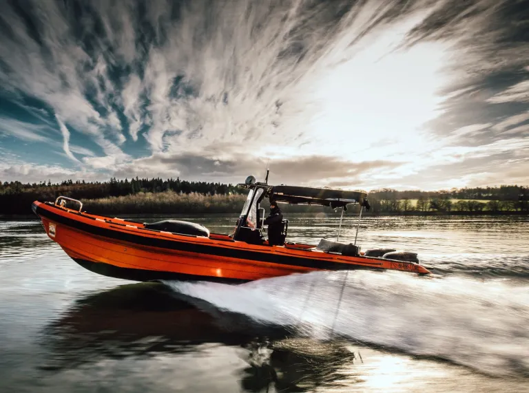 The RibRide boat speeding along the river with dramatic skies in the background.