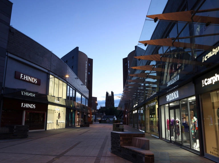 A shopping centre pedestrianised street during nightfall.