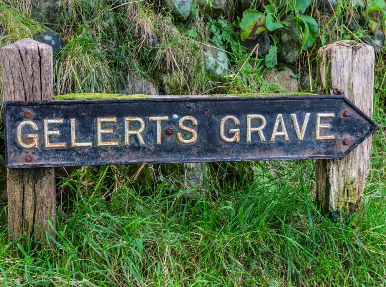 A steel signpost directing to the grave of a heroic dog.