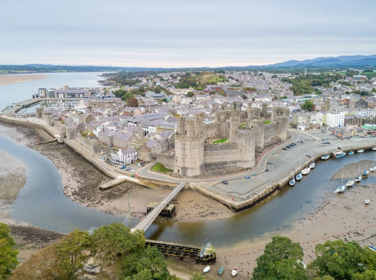 Aerial shot of a castle and town surrounded by an estuary.