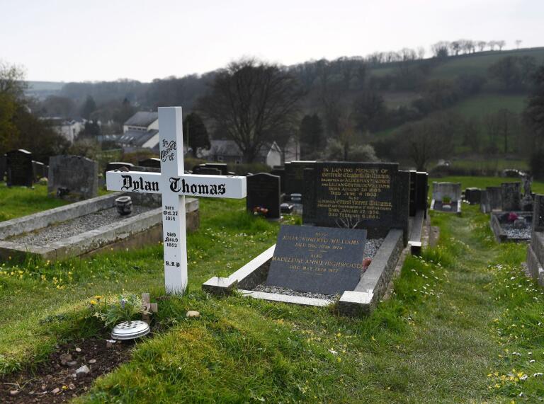 A white cross with Dylan Thomas' name and his grave at  St Martin's Church graveyard.