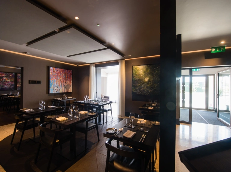 Tables and chairs in a restaurant with artwork on the walls.