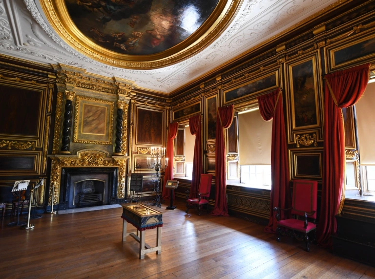 A grand room with an ornate fireplace and domed painted ceiling.