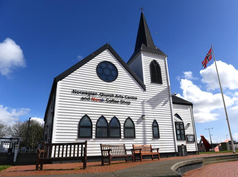 A white church on a sunny day with a flag flying outside.