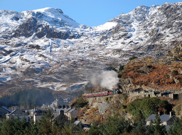 A steam train passing through a snowy slate quarry.