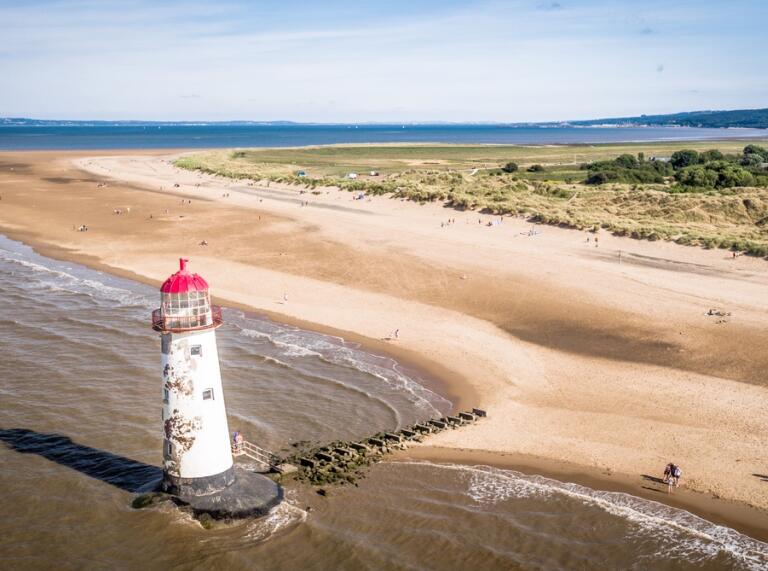 A lighthouse alongside the golden sand and unspoilt green pastures.