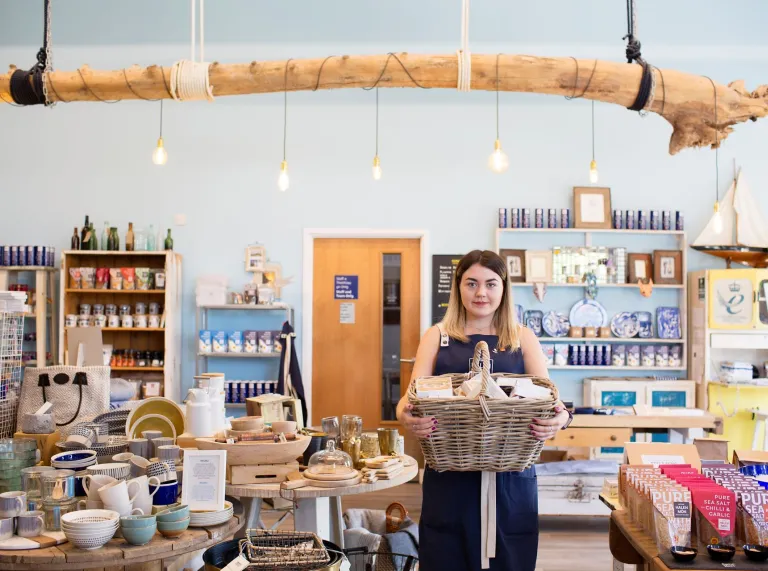 A woman in a gift shop holding a basket of produce.