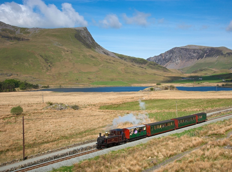 A steam train travelling through mountainous scenery.