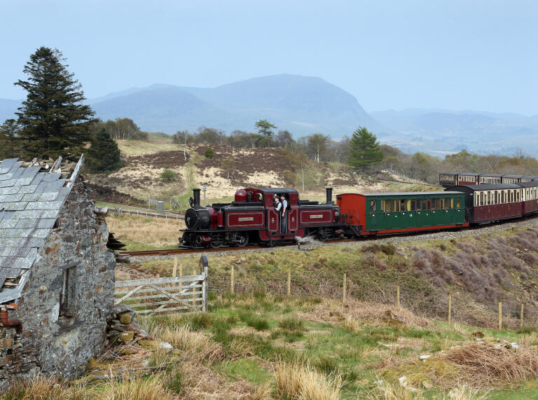 A steam train pulling carriages amongst scenic mountains and landscape.