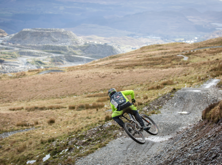 A|mountain biker going down the trail with views of the mountains.