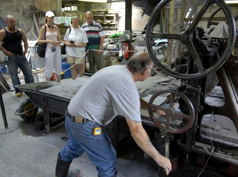 A man showing a group of visitors how one of the slate machines work at Inigo Jones Slate Workshops.