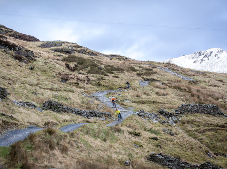 Two mountain bikers going down a bendy trail at Antur Stiniog.