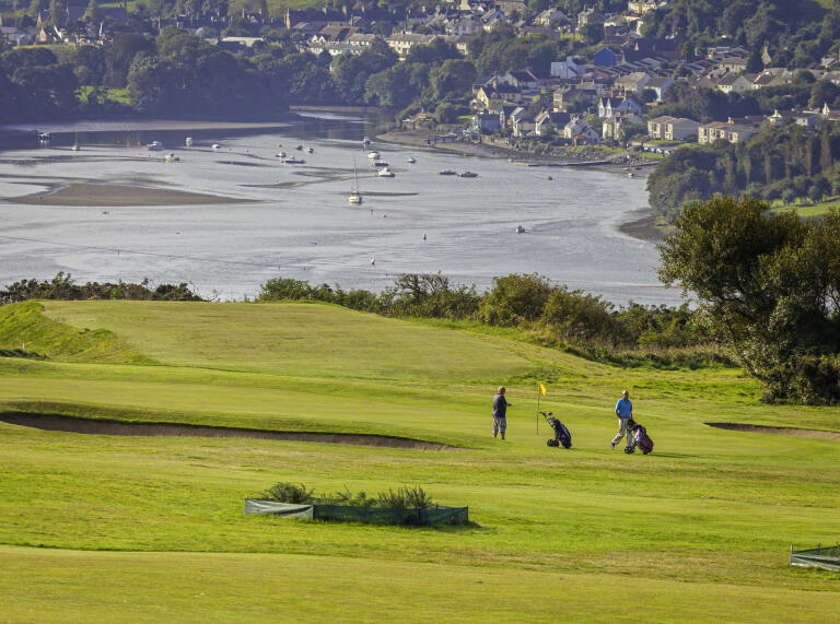 Golfers playing a round at Cardigan Golf Club with views of Cardigan bay in the background.