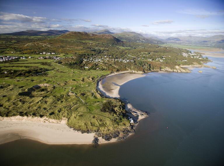Porthmadog golf course by the sea with mountains in the background.