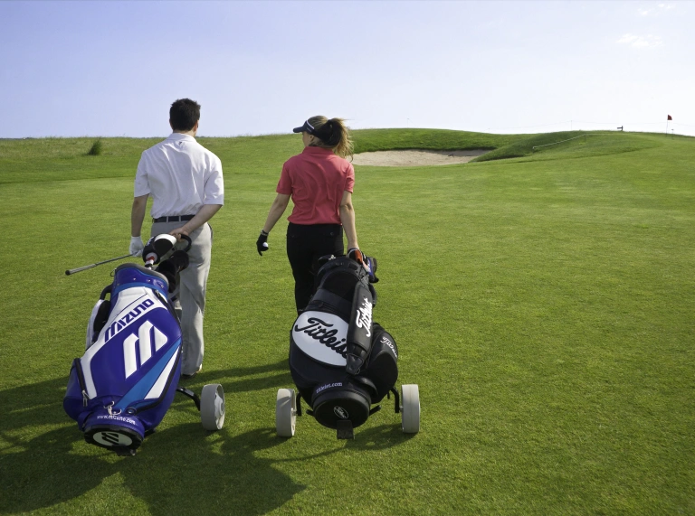 Man and woman golfing on Machynys golf course.