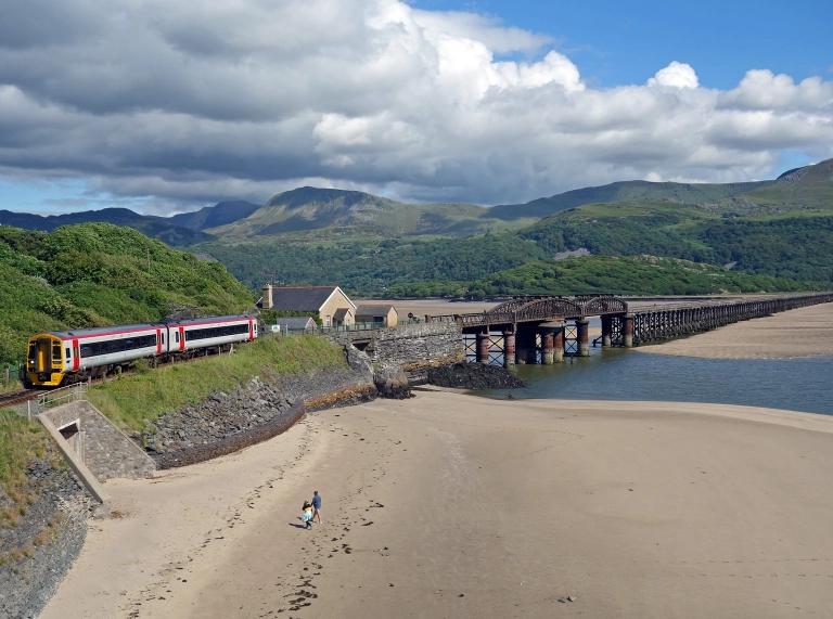 A train near Barmouth viaduct travelling between the mountains and coast.