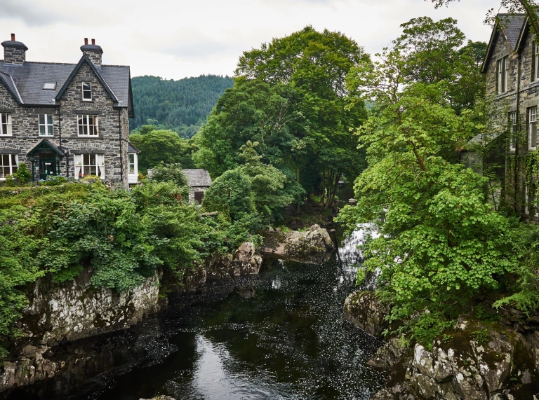 River and houses set amongst lush green trees in Betws-y-Coed.