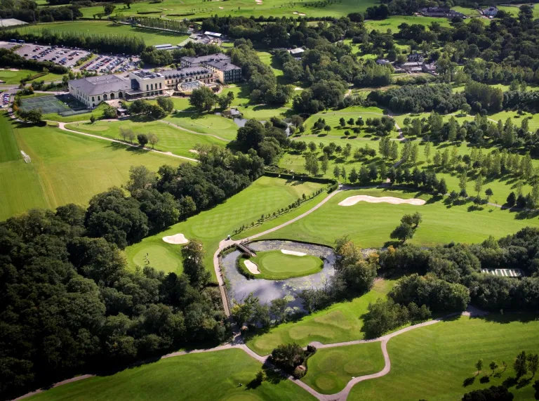 Looking down on the grounds of the resort, green grass and golf course with trees and hotel in the far background.