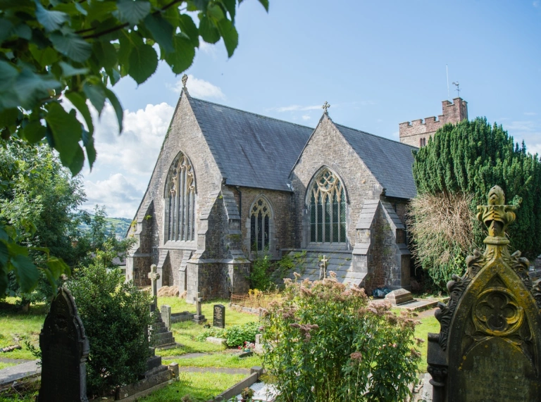 A church and graveyard framed by foliage.