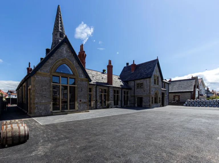 An old school building with barrels outside spelling Penderyn Distillery.