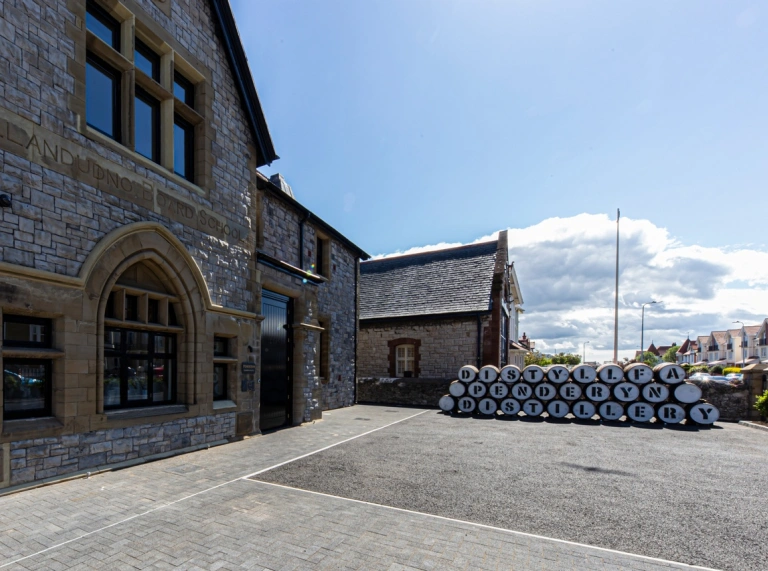 Outside Penderyn Distillery Llandudno with barrels and blue sky.