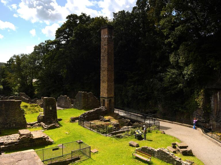 A large chimney amongst the ruins of a former tin works.