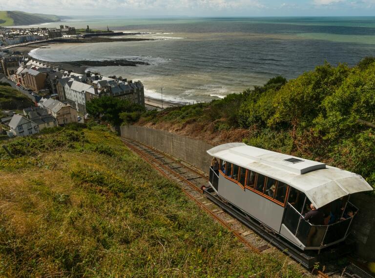 A cliff railway heading down a track with views of the coastal town.