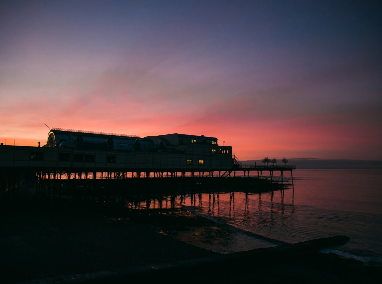 A pier with a dramatic sunset behind it.
