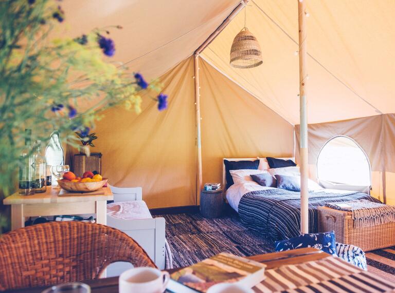 A bed and furnishings in a glamping tent.