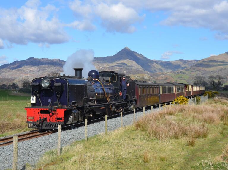 A steam train travelling through mountainous scenery.