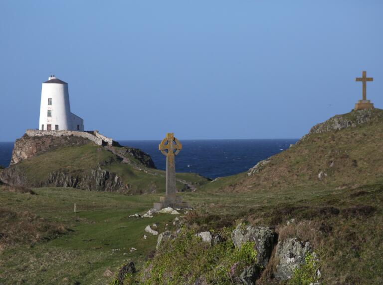 Celtic and Christian crosses near a lighthouse.