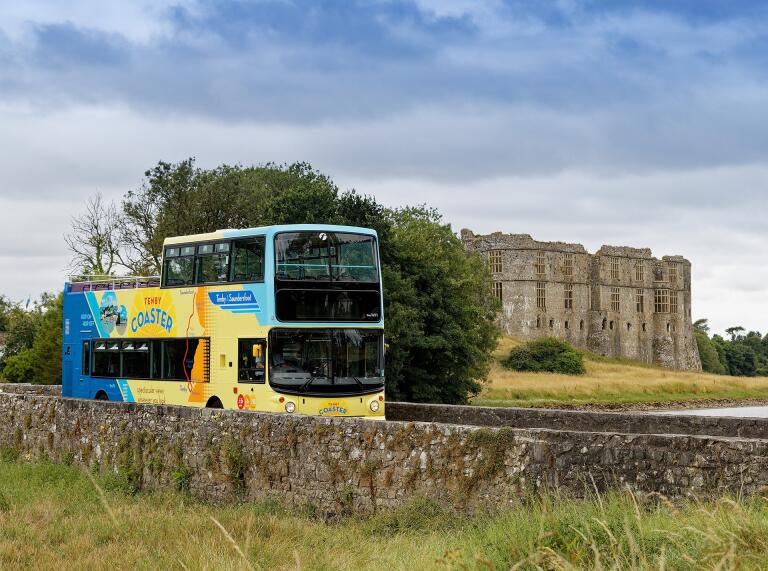 An open top bus travelling past a castle.