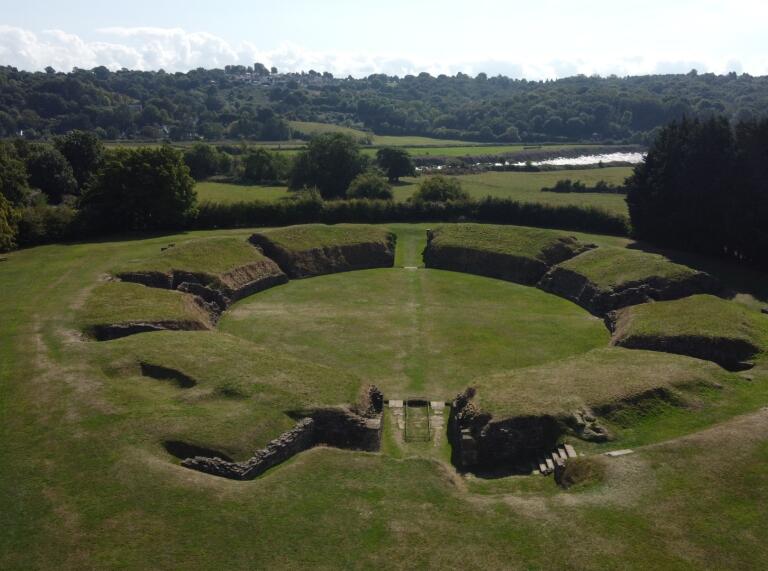 Aerial shot of an amphitheatre amongst green lush countryside.