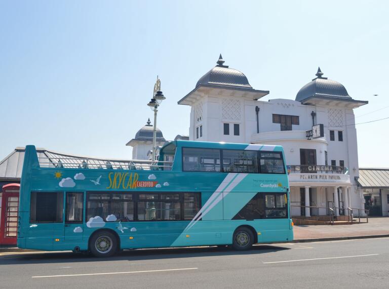 An open top bus at the bus stop by a pier.