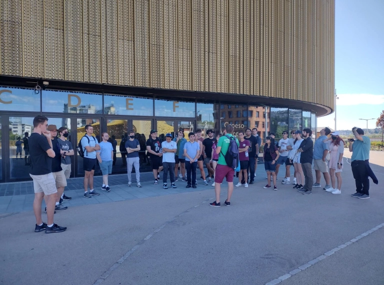 A group of people on a walking tour outside an arena.