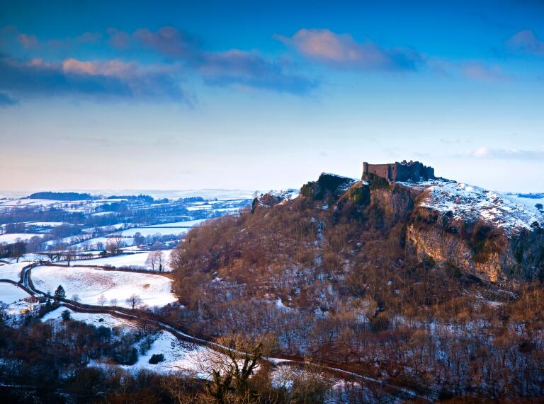 A castle on a hill surrounded by a snowy landscape.