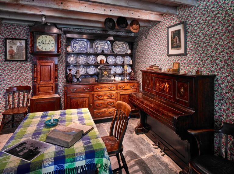 Dining table, piano, grandfather clock and dresser in an historic cottage.
