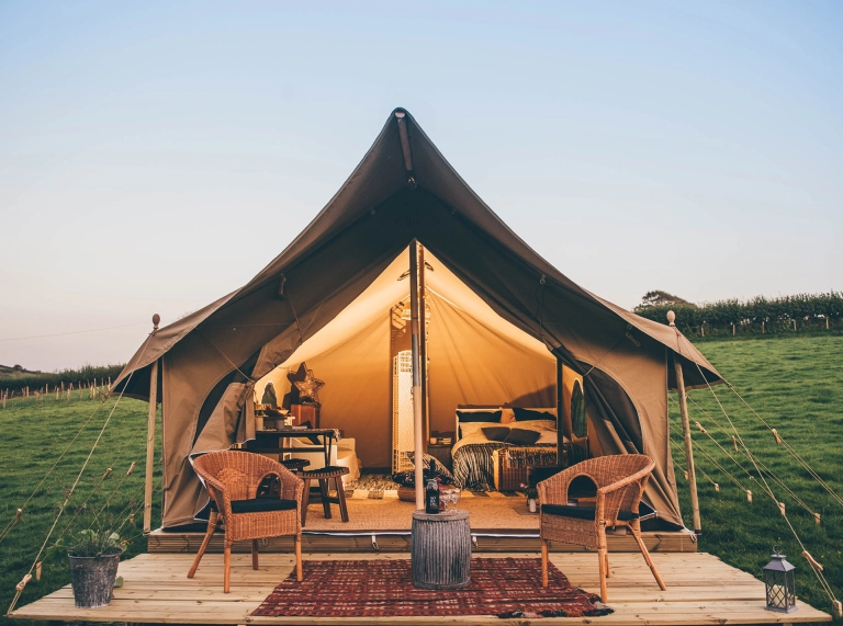 Canvas lodge with bed, chairs and table.