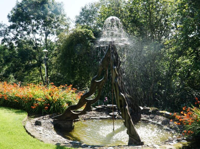 A tall fountain amongst beautiful gardens.
