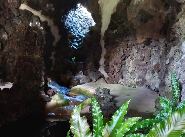 Inside a rock grotto with water flowing through it.