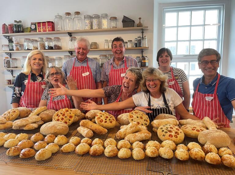 Group of people behind bread freshly made in baking school.
