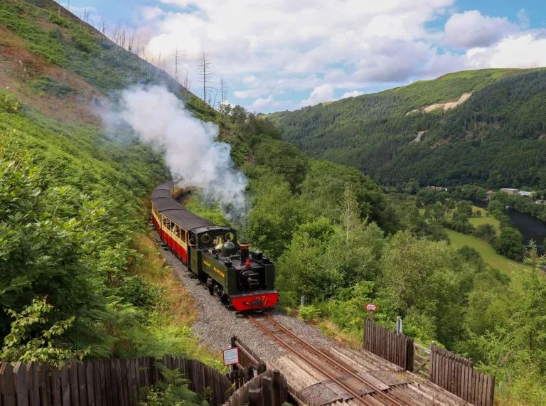 Steam train travelling through a valley.