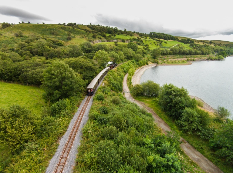 A train in the countryside passing a reservoir.